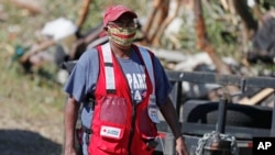 FILE - A Red Cross volunteer wears a face mask while visiting tornado-damaged residences in Prentiss, Miss., April 14, 2020. Additional storms on April 19, 2020, were blamed for three deaths. 