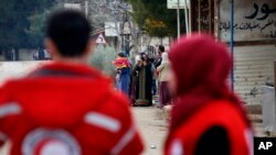 FILE - Members of the Syrian Red Cross stand near aid vehicles in the besieged town of Madaya about 15 miles (24 kilometers) northwest of Damascus, Syria, Jan. 11, 2016. Red Cross trucks were refused entry Thursday in the Syrian town of Daraya.