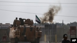 Turkish-backed Syrian opposition fighters on an armored personnel carrier drive to cross the border into Syria, in Akcakale, Sanliurfa province, southeastern Turkey, Oct. 18, 2019. 