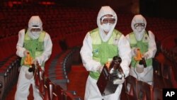 Para pekerja mengenakan pakaian pelindung saat menyemprotkan cairan antiseptik untuk mencegah wabah MERS di Seoul, Korea Selatan (16/6).
