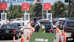 Petugas lalu-lintas mengarahkan mobil-mobil melalui lantatur (drive-through) tes Covid-19 di Stadion Dodgers, Los Angeles, California, 15 Juli 2020. (Foto: AFP)