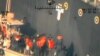 This image released by the Pentagon June 17, 2019, and taken from a U.S. Navy helicopter, shows what the Navy says are members of the Islamic Revolutionary Guard Corps Navy removing an unexploded limpet mine from the M/T Kokuka Courageous.