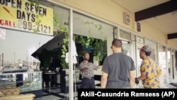 In this April 30, 1992 file photo, store owner Chris, left, talks to his friends from the wreckage of his store in the Crenshaw Shopping Center off Slauson and Crenshaw in Los Angeles. (AP Photo/Akili-Casundria Ramsess)