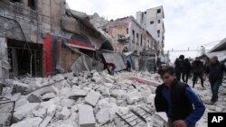 FILE - People walk past debris following airstrikes by government forces, in the town of Ariha, Idlib province, Syria, Jan. 15, 2020. 