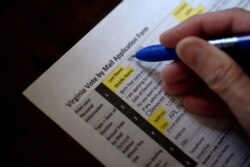 This illustration photo shows a Virginia resident filling out an application to vote by mail ahead of the November Presidential election, on Aug. 6, 2020, in Arlington, Virginia.