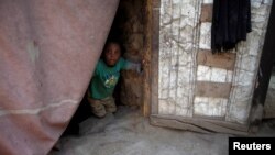 Seorang bocah yang mengungsi dari kota pelabuhan Laut Merah Hodeida terlihat dari balik tirai pintu di tempat penampungan di Sanaa, Yaman, 2 November 2018. (Foto: dok).