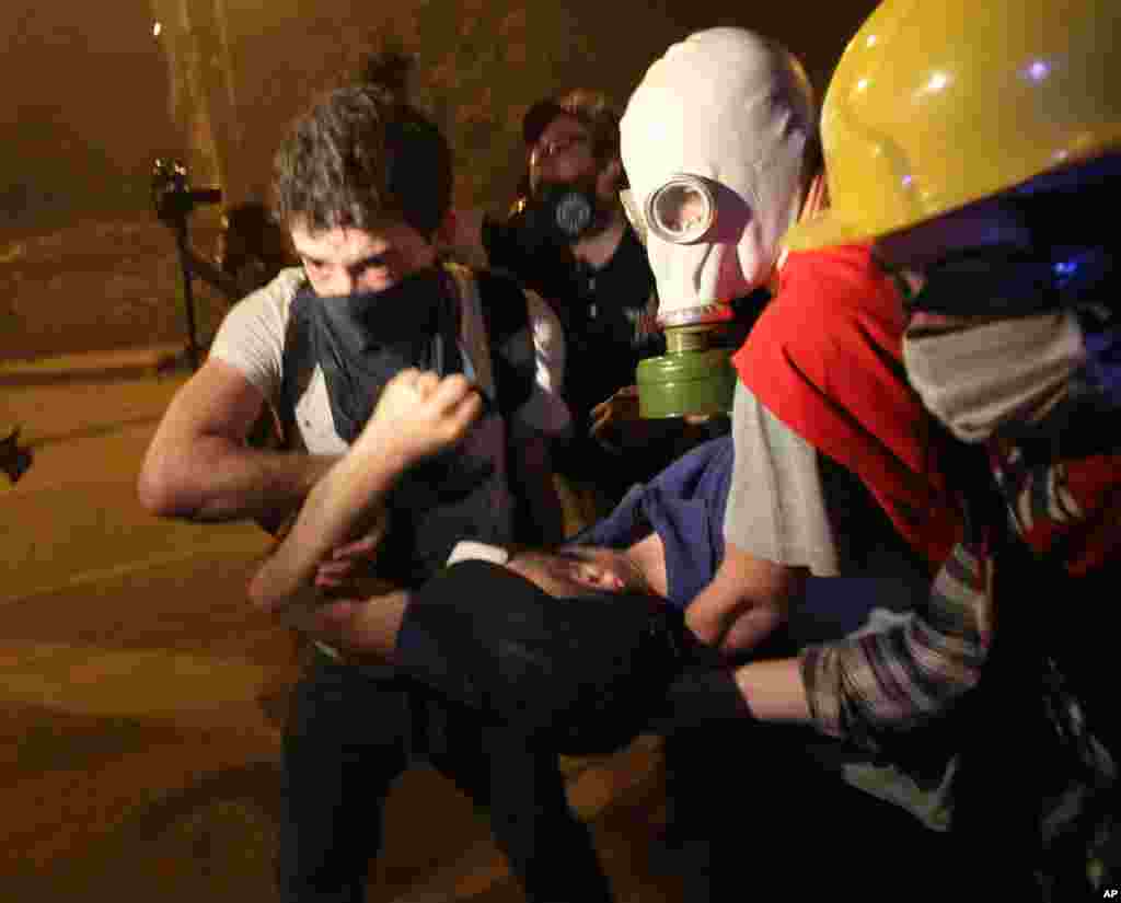 Para anak muda membawa demonstran yang terluka dalam protes anti-pemerintah di Besiktas, Istanbul (2/6). (AP/Thanassis Stavrakis)&nbsp;