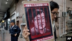 FILE - A protester holds a picture of imprisoned and prominent Chinese human rights lawyer Wang Quanzhang during a protest outside the Chinese liaison office in Hong Kong, July 13, 2018.