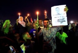 Sudanese protesters hold candles near a portrait of a civilian killed in a march, during a demonstration to commemorate 40 days since a sit-in massacre in Khartoum North, Sudan, July 13, 2019.