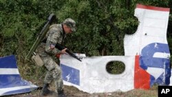 Proruski pobunjenik kod delova olupine aviona Malezija Erlajnza na polju u istočnoj Ukrajini, 9. septembra 2014. 