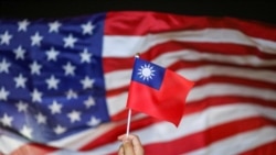 FILE - An anti-government protester holds a Taiwan national flag as a US flag flutters in the background during a demonstration to celebrate Taiwan's National Day in Hong Kong, China Oct. 10, 2019.