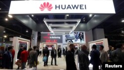 FILE - Attendees pass by a Huawei booth during the 2019 CES in Las Vegas, Nevada, U.S. Jan. 9, 2019. 