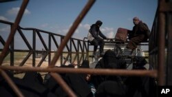 Men, women and children ride in the back of a truck in a convoy evacuating hundreds out of the last territory held by Islamic State militants in Baghuz, eastern Syria, Feb. 22, 2019. 