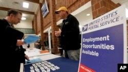 FILE - A recruiter from the postal service, right, speaks with a job fair attendee in Cheswick, Pa.