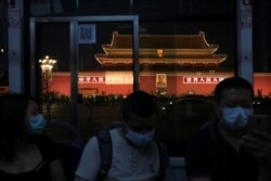 People wearing face masks, following the coronavirus disease outbreak, ride a bus past a portrait of late Chinese chairman Mao Zedong on Tiananmen Gate, in Beijing on June 3, 2020.