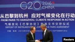 Le président américain Barack Obama, à droite, se serre la main avec le secrétaire général de l'ONU Ban Ki-moon lors d'une cérémonie de ratification conjointe de l'accord sur le changement climatique de Paris avant le sommet du G20 au Guest House de l'Etat, le 3 septembre 2016.