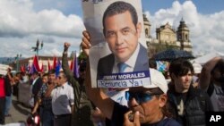 បុរស​ម្នាក់​កាន់​រូបថត​ប្រធានាធិបតី​ក្វាតេម៉ាឡា Jimmy Morales ក្នុង​ពេល​ធ្វើ​បាតុកម្ម​បង្ហាញ​ការ​គាំទ្រ​ដល់​លោក Ivan Velasquez បេសកជន​អង្គការ​សហប្រជាជាតិ​ផ្នែក​បេសកកម្ម​អន្តរជាតិ​ប្រឆាំង​នឹង​និទណ្ឌភាព​ ក្នុង​ទីក្រុងក្វាតេម៉ាឡា កាល​ពី​ថ្ងៃ​ទី​២៦ ខែ​សីហា។