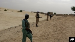 In this Sept. 16, 2012 photo, members of Islamist group Ansar Dine stand guard as they prepare to amputate the hand of a young man found guilty of stealing rice in Timbuktu, Mali. 