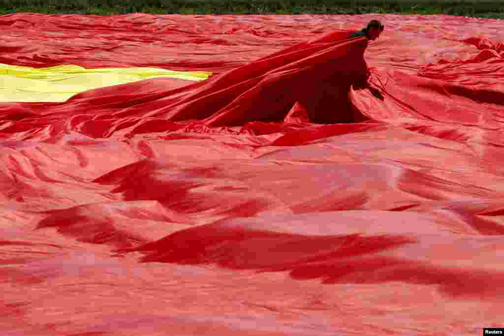 Seorang pekerja mengatur bendera nasional Rumania dalam upaya untuk mencetak Rekor Dunia Guinness bendera terbesar di dunia, di kota Clinceni, dekat Bucharest. 