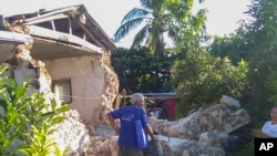 Seorang warga memeriksa rumah-rumah yang rusak di Kota Itbayat, kepulauan Batanes, utara Filipina, 27 Juli 2019. 