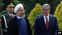 Turkey's President Abdullah Gul, right, and his Iranian counterpart Hassan Rouhani speak as they walk together during a ceremony at the Cankaya Palace in Ankara, Turkey, June 9, 2014. 