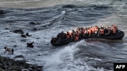 Refugees and migrants try to reach the shore on the Greek island of Lesbos, despite a rough sea, after crossing the Aegean Sea from Turkey, Oct. 30, 2015.