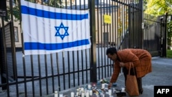 2023年10月9日，巴勒斯坦激进组织哈马斯对以色列发动突然袭击后，一名妇女在以色列驻瑞典斯德哥尔摩大使馆外放置蜡烛以表示声援和支持。（法新社照片）
