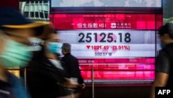 Pedestrians walk past an electronic sign displaying the Hang Seng Index in Hong Kong, March 9, 2020. Hong Kong stocks ended Monday's morning session sharply lower, in line with a rout across Asia, on coronavirus fears.
