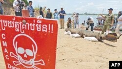 Journalists take photograph of a bomb pulled from the murky depths of the Mekong River on Thursday. 