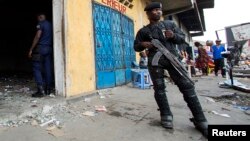 Un policier monte la garde devant un magasin pillé lors de violentes manifestations à Kinshasa, en République démocratique du Congo, 23 janvier 2015.