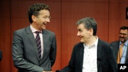 Ketua Eurogroup Jeroen Dijsselbloem (kiri) bersalaman dengan Menkeu Yunani Euclid Tsakalotos dalam pertemuan di Brussels, Jumat (14/8).