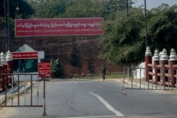 A soldier stands guard at a checkpoint next to a military propaganda billboard in Mandalay, Myanmar, Feb. 3, 2021.