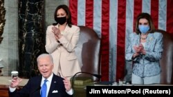 Le président américain Joe Biden s'adresse à une session conjointe du Congrès sous le regard de la vice-présidente Kamala Harris (à g.) et de la présidente de la Chambre des représentants Nancy Pelosi au Capitole à Washington, aux États-Unis, le 28 avril 2021. 