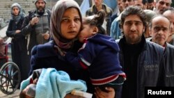 FILE - Residents line up to receive humanitarian aid at the Palestinian refugee camp of Yarmouk, in Damascus, Syria, March 2015. 
