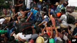 Central American migrants, part of one of the caravans hoping to reach the U.S. border, scramble to get a ride on a truck, in Isla, Veracruz state, Mexico, Nov. 3, 2018. The 150 buses that the governor of Veracruz promised to the migrants to get to Mexico City did not arrive.