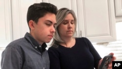 ARSIP – Grant Thompson dan ibunya, Michele, melihat ke sebuah iPhone di dapur keluarga di Tucson, Atizone, 31 Januari 2019 (foto: AP Photo/Brian Skoloff, Arsip)