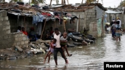 Wani mutum dauke da yaransa bayan da guguwar Idai ta ratsa ta yankin Beira a aksar Mozambique, Maris 23, 2019. 