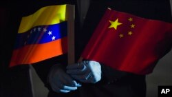 Menteri Luar Negeri Venezuela Jorge Arreaza memegang bendera Venezuela dan China. (Foto: AP)