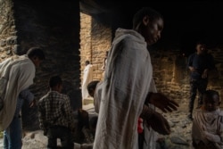 At the oldest church in Axum, Ethiopians collect ashes from a pit fire that is believed to be blessed, in Axum, Ethiopia, June 11, 2021. (Yan Boechat/VOA)