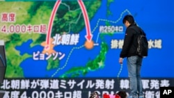 A man stands in front of a huge screen showing TV news program reporting North Korea's missile launch, in Tokyo, Nov. 29, 2017. 