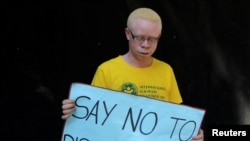 Un Albinos porte une pancarte "Dites non à la discrimination" lors d'une campagne de sensibilisation à Harare, Zimbabwe, le 18 juin 2016.