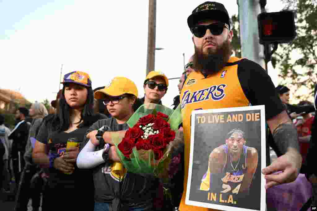 Bryan Stange, right, stands with his family holding a sign near the scene of a helicopter crash that killed former NBA basketball player Kobe Bryant in Calabasas, Calif., Jan. 26, 2020.