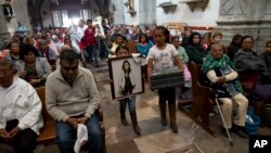 Relatives of murdered doctor and mother, Jessica Sevilla Pedraza, carry a framed portrait of her, a cross, and a box of mementos to be buried alongside her grave, as they arrive for Mass in Villa Cuauhtemoc, Mexico state, Aug. 18, 2017.