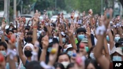 Anti-coup protesters raise decorated Easter eggs along with the three-fingered symbols of resistance during a protest against the military coup on Easter, April 4, 2021, in Yangon, Myanmar. 