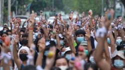 Anti-coup protesters raise decorated Easter eggs along with the three-fingered symbols of resistance during a protest against the military coup on Easter, April 4, 2021, in Yangon, Myanmar.