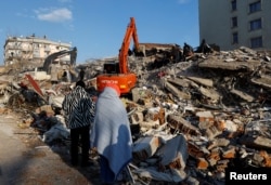 Warga melihat puing-puing dan reruntuhan setelah gempa bumi di Kahramanmaras, Turki, 8 Februari 2023. (Foto: REUTERS/Suhaib Salem)