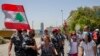 An anti-government protester yells as she and others block a main highway outside the Ministry of Energy and Water after scuffling between protesters and riot police, in Beirut, Lebanon, May 21, 2020.