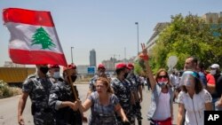 An anti-government protester yells as she and others block a main highway outside the Ministry of Energy and Water after scuffling between protesters and riot police, in Beirut, Lebanon, May 21, 2020.