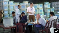 Afghan election commission workers sort ballots for an audit of the presidential run-off votes in front of international observers at an election commission office in Kabul, Aug. 27, 2014. 