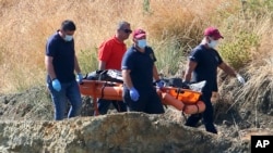 A crew carries what are believed to be remains of a 6-year-old girl, near Xiliatos, Cyprus, June 12, 2019. The remains are thought to be those of a victim of a confessed serial killer, a 35-year-old Cyprus army captain.
